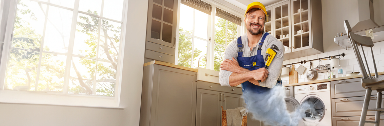 Handwerker mit Schraubenschlüssel erscheint aus Waschmaschine - Zuhause-Schutzbrief ADAC